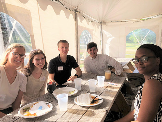 Four people sitting at a table outside eating